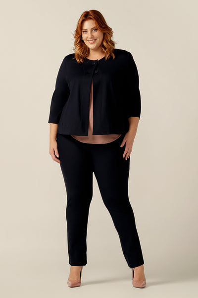 A plus size, size 18 woman wears a round neck navy work wear jacket with 3/4 sleeves