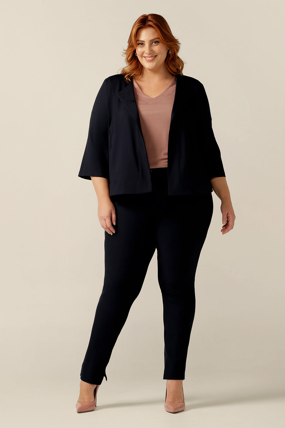 A plus size, size 18 woman wears a round neck navy work wear jacket with 3/4 sleeves