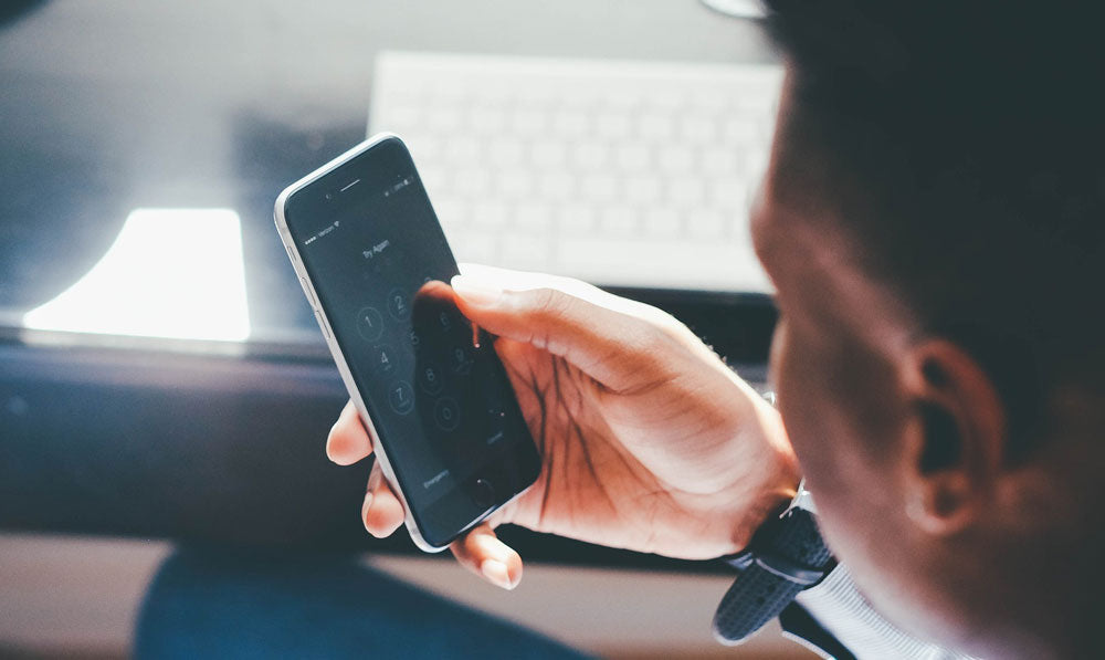 Man holding smartphone at computer desk