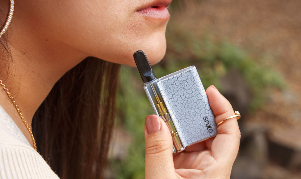 Woman holding Exxus White Black Crackle Palm Pro in front of forest clearing