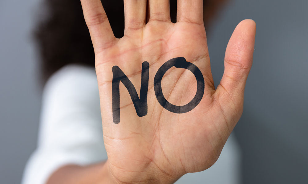 Woman holding up a hand with the word "no" on her palm