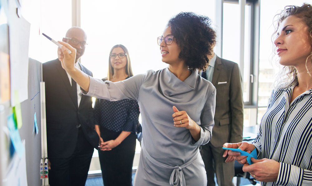 Group of professionals pointing at white board with plans