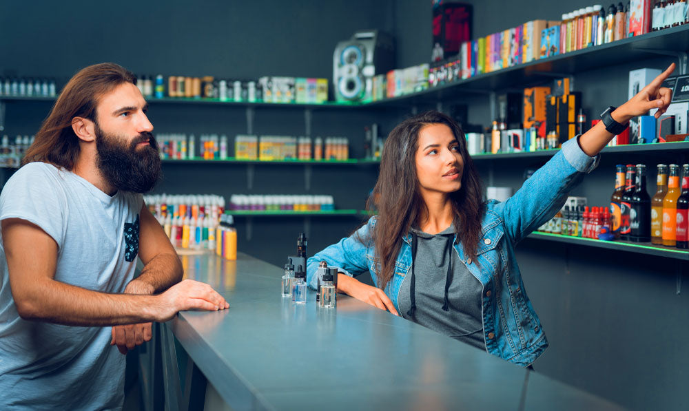 Employee in a smoke shop pointing out products to a customer