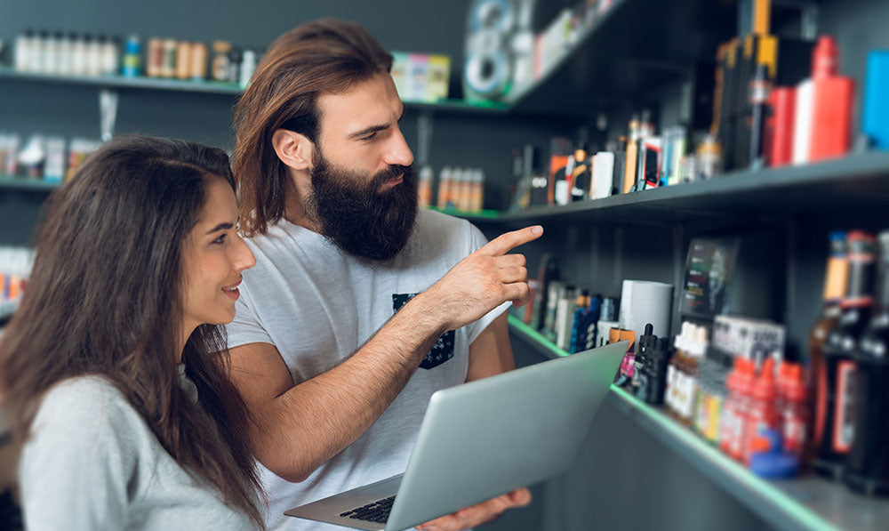 Hombre y mujer revisando el inventario en su tienda de humo.