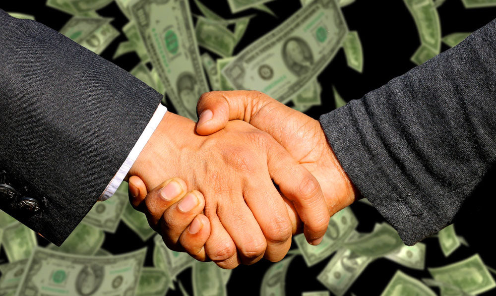 Two men shaking hands with money falling behind them