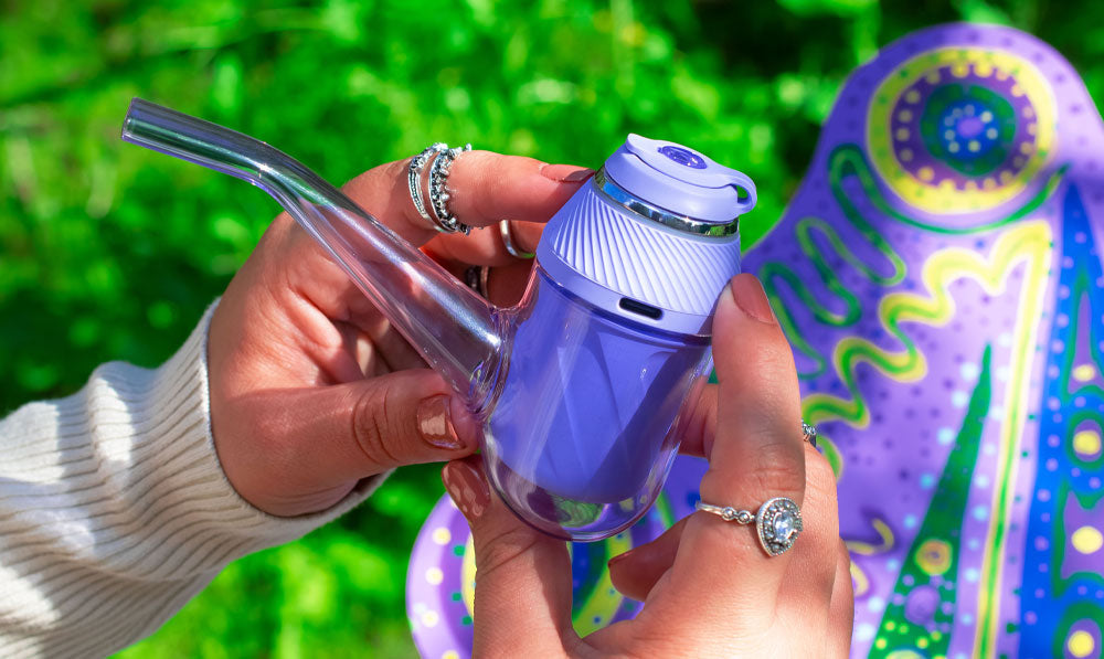 Woman holding Puffco Proxy Bloom in front of forest background