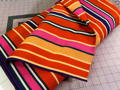 Bolt of striped Guatemalan fabric in orange, pink, and yellow