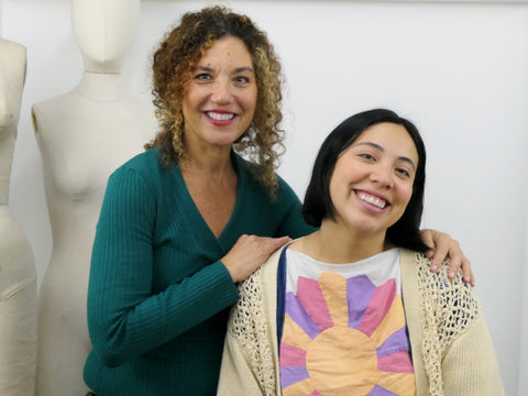 two women posing in front of a white backdrop