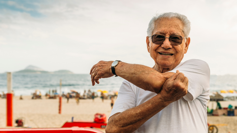 Tan older adult doing crossover arm stretch 