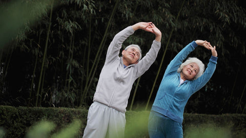 An older man and woman stretching outside