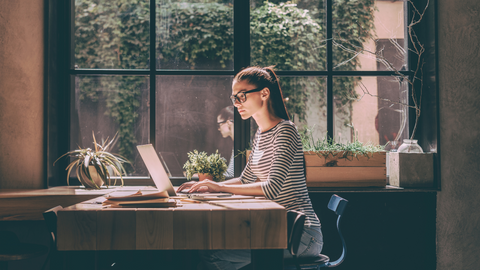 Woman sitting at a table working on her laptop. 