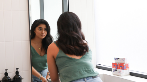 Woman looking at her self in the mirror. 