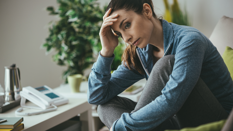 Woman sitting at her work table, looking upset and stressed. 