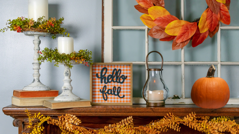 Hello Fall. Table with fall decorations: pumpkins, flowers, candles, and leaf garland.