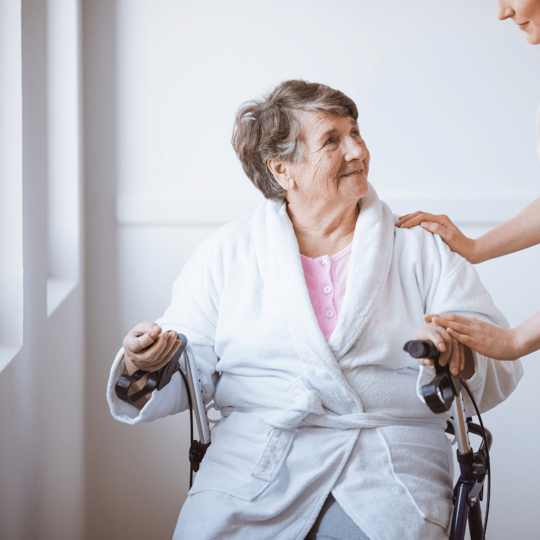 older woman sitting in walker with caregiver