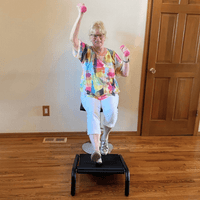 Older adult walking at her own pace while seated with the Sitmill and working her upper body with handweights