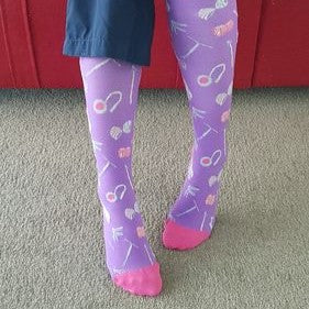 Person wearing purple patterned tights with pink toes standing on carpet.