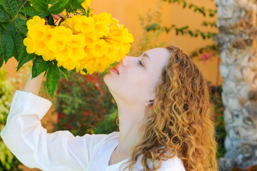 a woman smells a bright yellow flower
