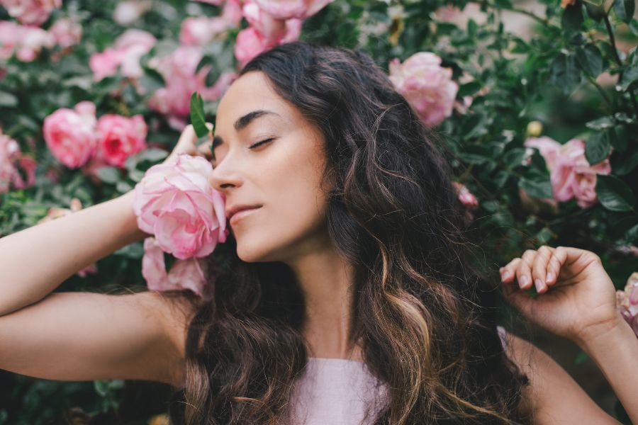 a woman smells fresh roses in a field