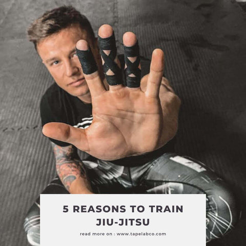 featured-picture-for-blog-post-5-reasons-why-you-should-start-training-brazilian-jiu-jitsu-guy-sits-on-the-floor-and-holds-his-hand-into-the-camera