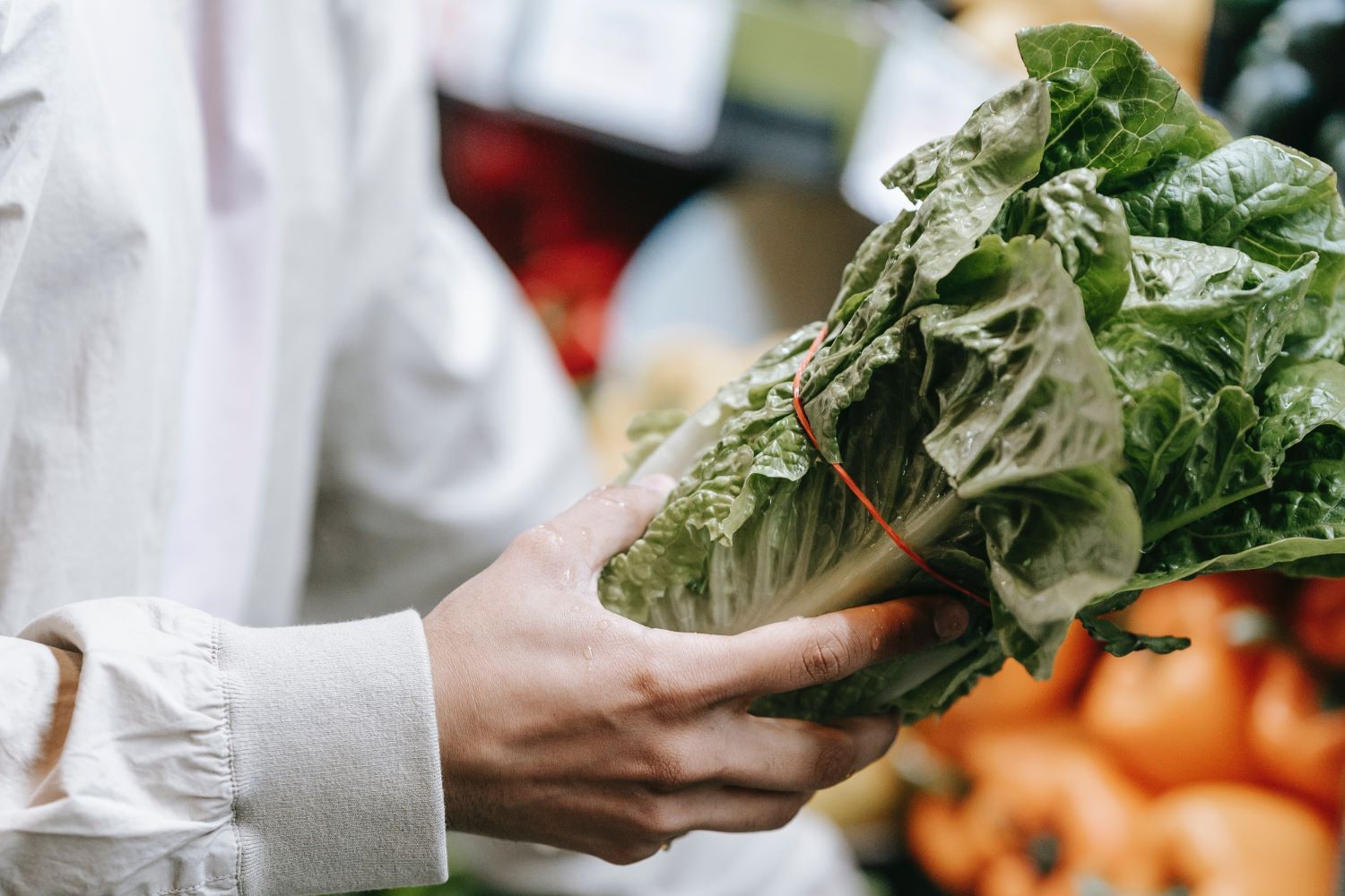 Anonymous customer picking greens in supermarket