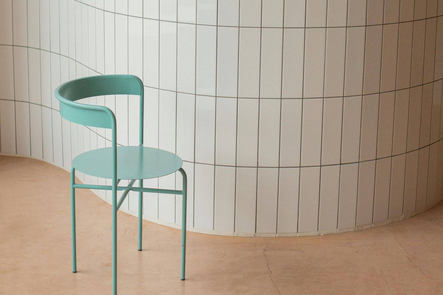 Chair near wall with ceramic tile and white placard