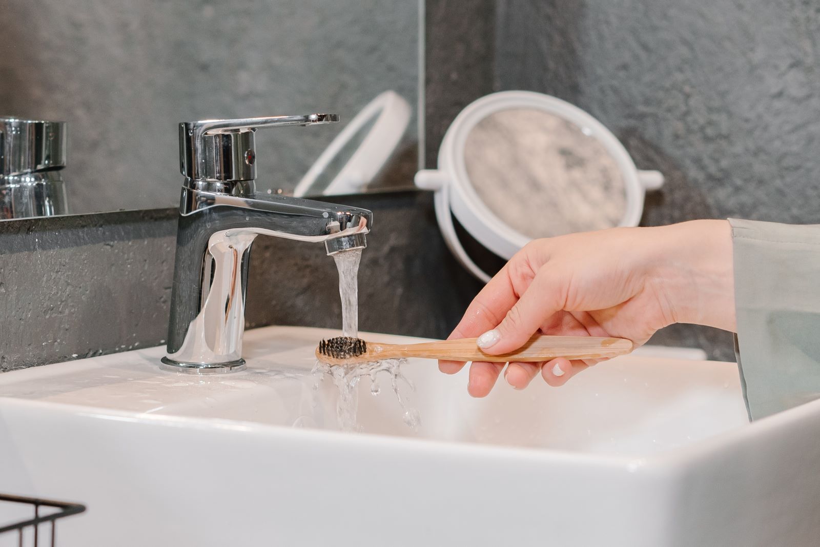 Close-Up Shot of a Person Washing a Bamboo Toothbrush on a Sink