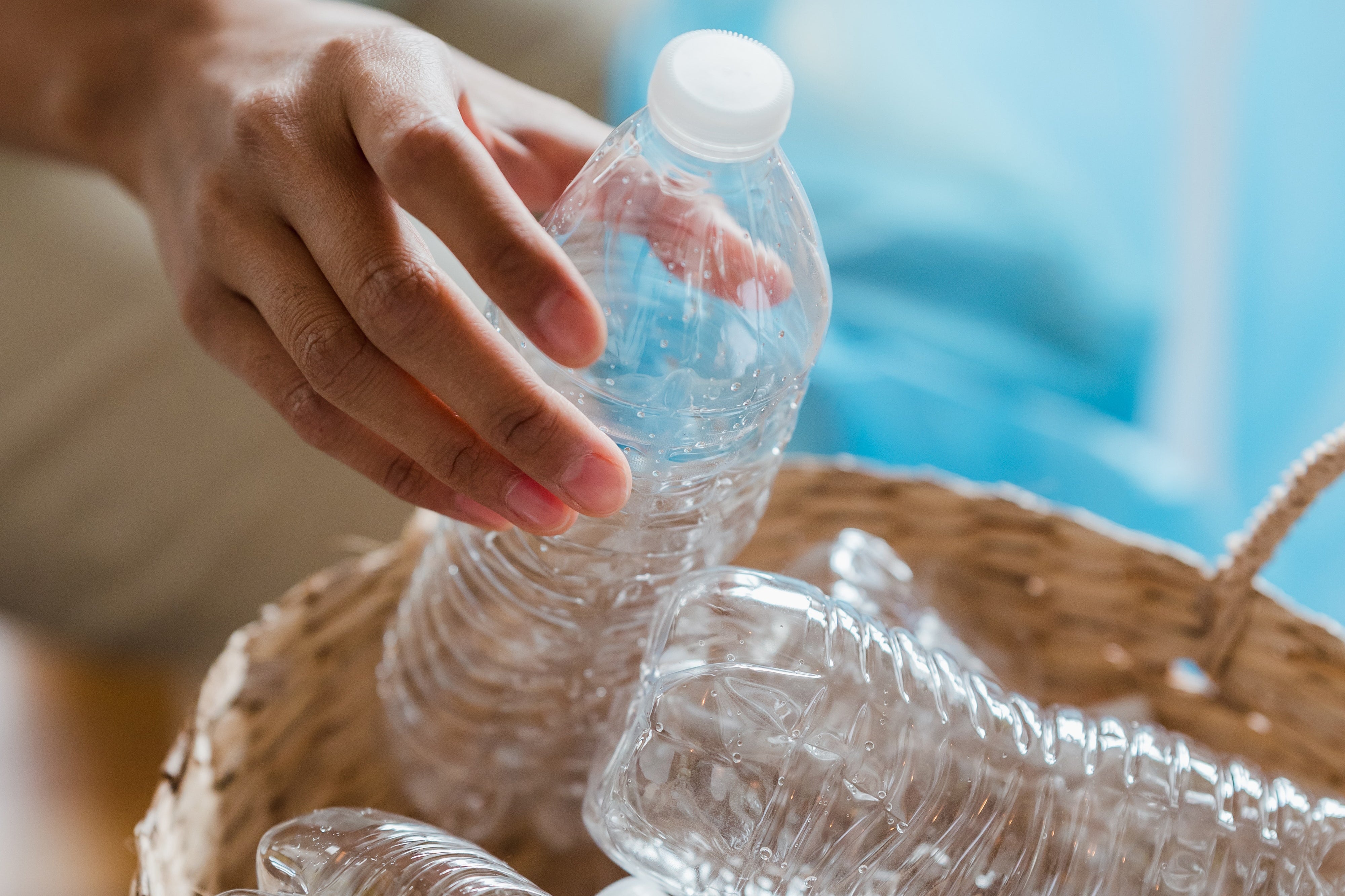 Person Putting Empty Plastic Bottles in a Basket