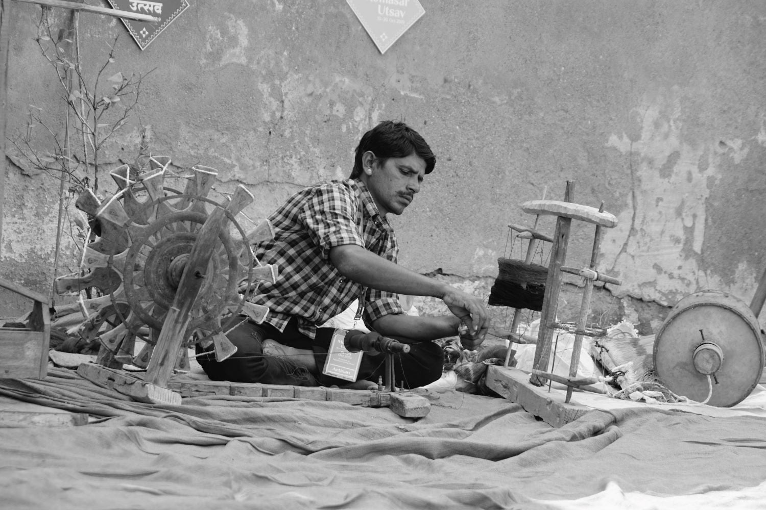 Serious ethnic man weaving textile on street