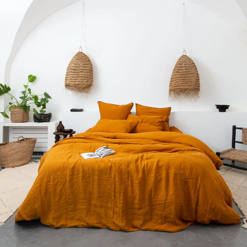 Bed with orange duvet cover in a white room