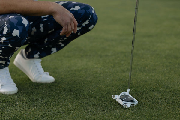 Man crouching down with a putter in hand