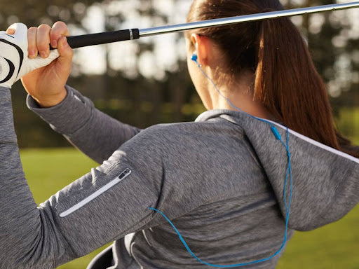 Woman wearing gray golf hoodie with arm pockets | golf glove | golf putt