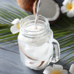 A glass of coconut water rests on a wooden table.