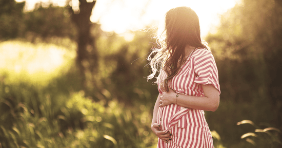 A pregnant woman walks outdoors.