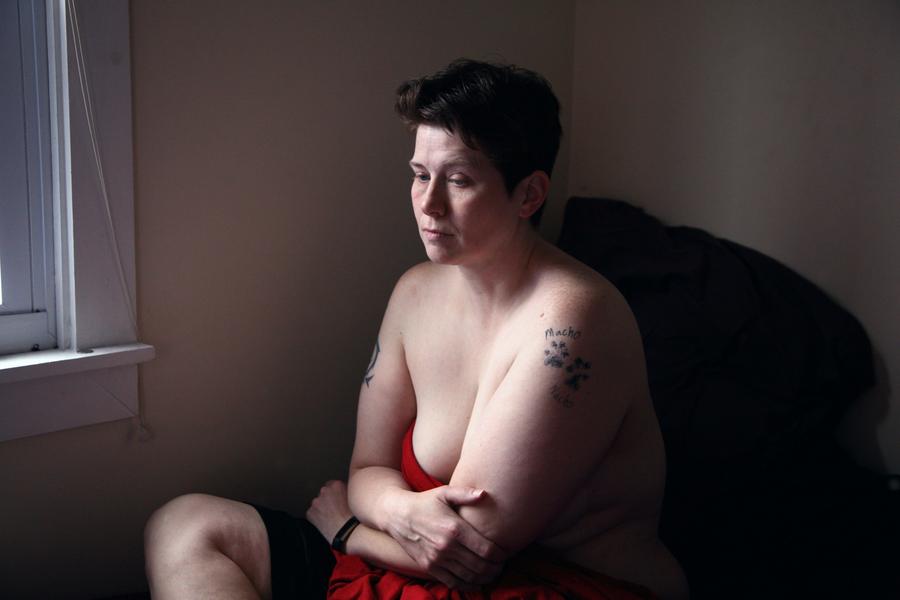 A woman in post-partum depression sits with her arms crossed.