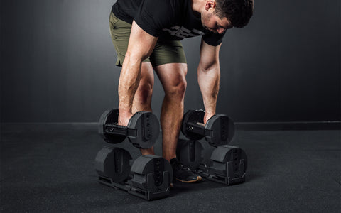 Athlete lifting a pair of REP x PÉPIN FAST Series Adjustable Dumbbells out of their cradles.