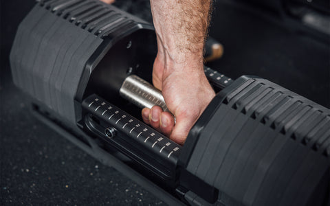 Close-up view of an athlete gripping the fully knurled handle of a REP x PÉPIN  FAST Series Adjustable Dumbbell.