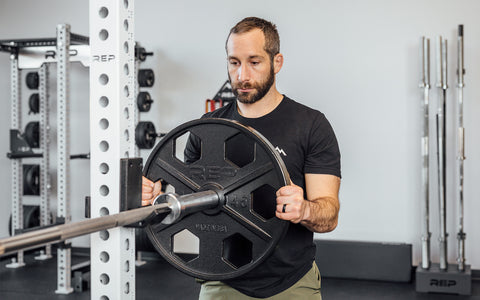 Man putting an iron plate on a barbell