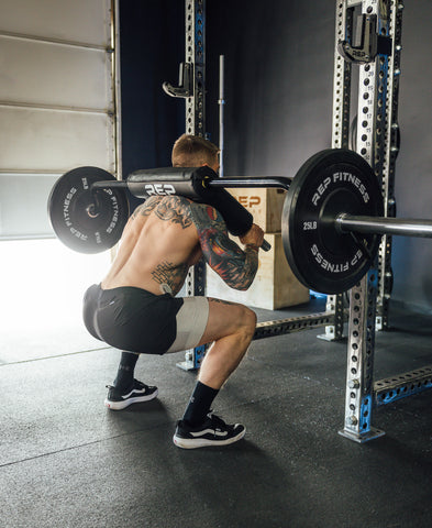 A man doing squats with a safety squat bar