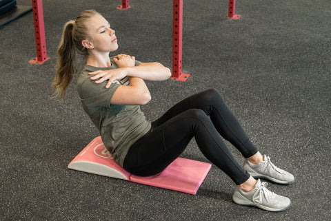 A woman doing sit-ups on an ab pad