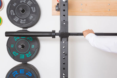 Lifter racking a black barbell on a squat rack