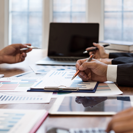 a group of business people sitting at a table with a laptop and papers