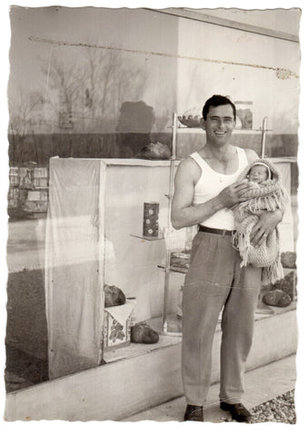 Tarcisio con in braccio il figlio Federico davanti alla rivendita. Anno 1960.