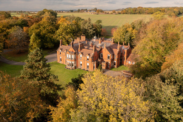 Rainford Hall - a red brick building, shot from above in the beautiful setting of trees and picturesque green land