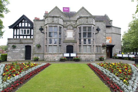 The front of Port Sunlight Museum Shop with a luscious green lawn and beautiful flowers in the foreground.