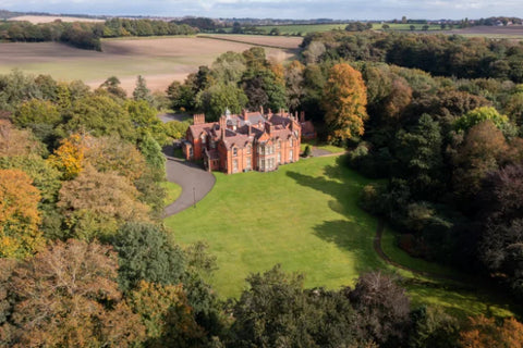 Rainford Hall - a red brick building sitting in acres of beautiful countryside with a mix of green and autumnal trees all around