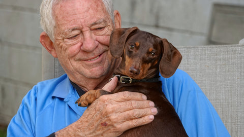 Persona mayor con perro salchicha