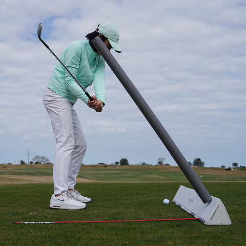 Golfer swinging under foam noodle and alignment stick to stop an over the top move