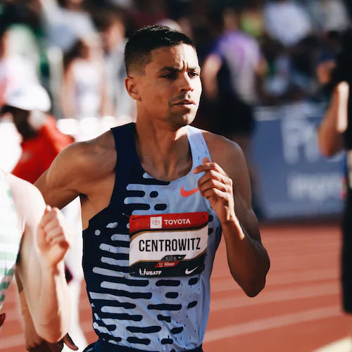 A man running on a track during a race wearing a blue and white uniform.
