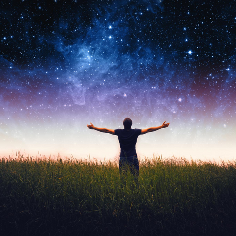 A man spreading his arms out towards a starry night sky, appreciating open-mindedness and positivity.